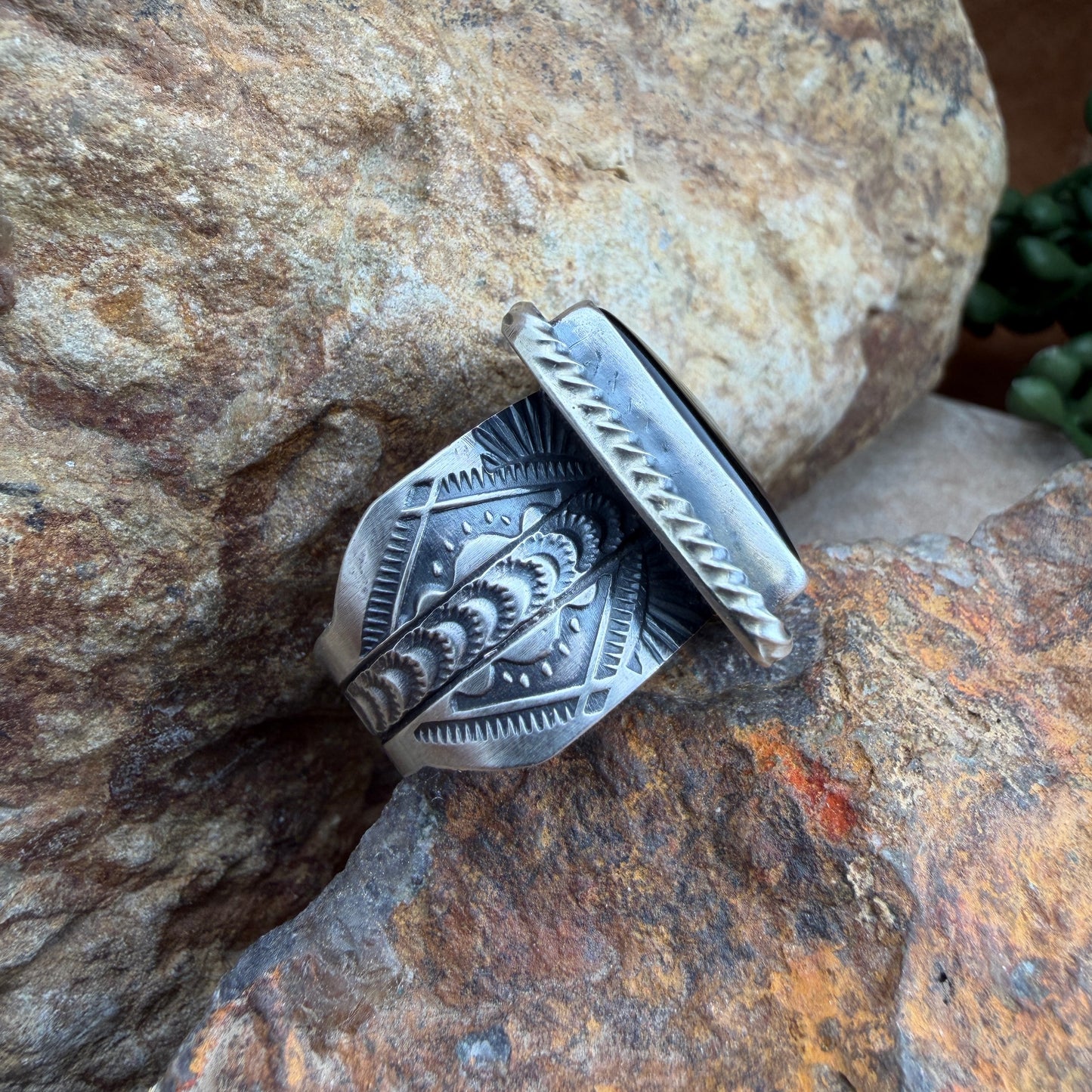 Silver ring with intricate designs on a stone surface