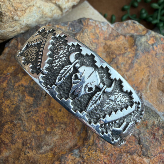 Silver bracelet with intricate designs of a buffalo skull, landscape, and eagle