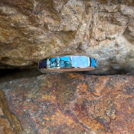 David Rosales Sterling Silver Ring with multicolor inlay. Inlaid with purple, turquoise and opal. it is resting in-between two rocks.