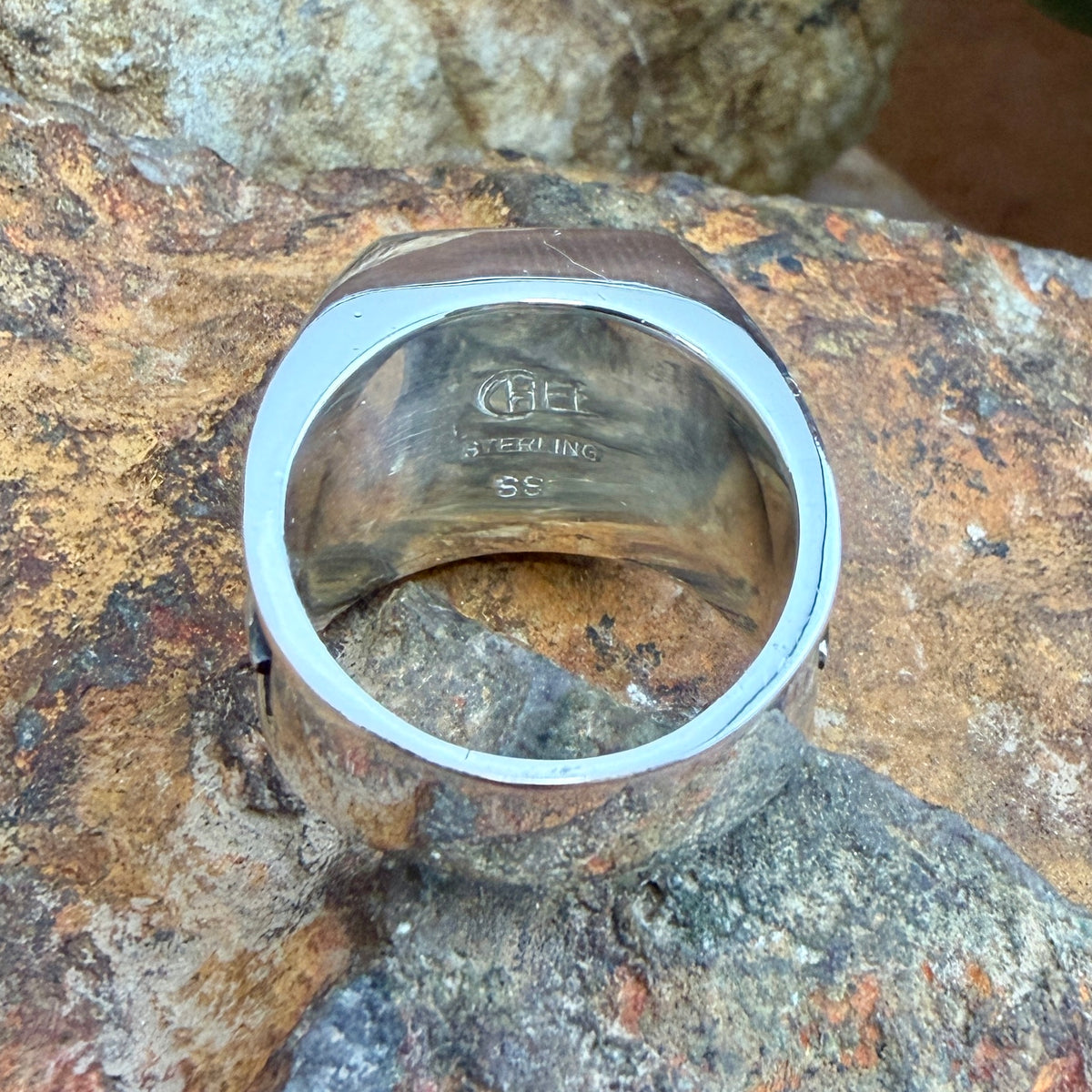 The inside of sterling silver band that features the stamping of the supersmith company, sterling, and the individual artist that worked on this piece.