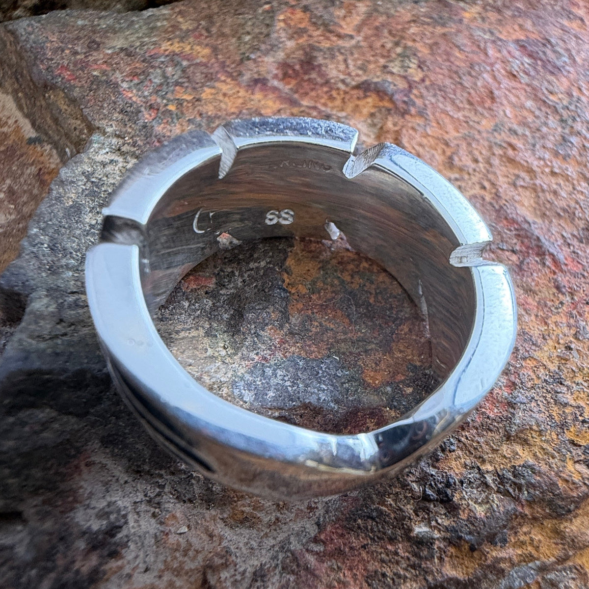 Inside of a silver ring showcasing SS stamping and "Sterling"
