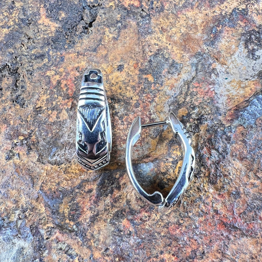 Silver ring and silver hoop earring on a textured stone surface
