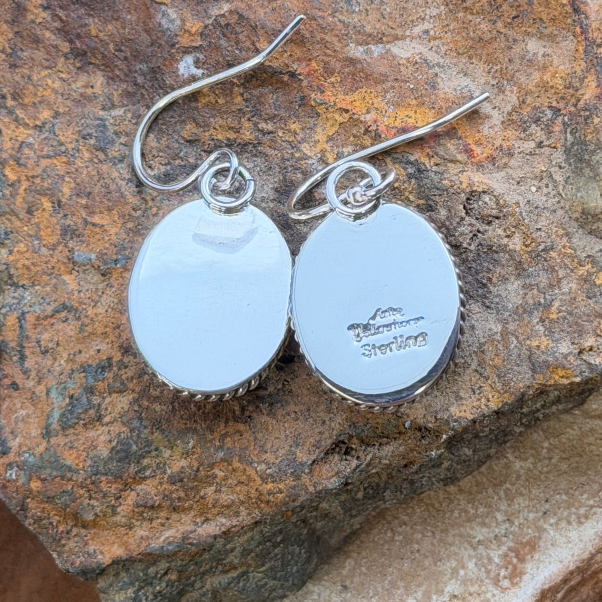 Front view of oval denim-blue lapis dangle earrings with twisted-rope sterling silver borders