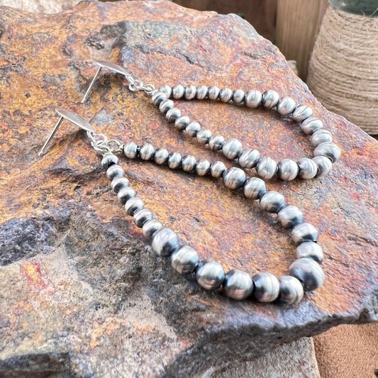 Silver beaded necklace on a textured stone surface