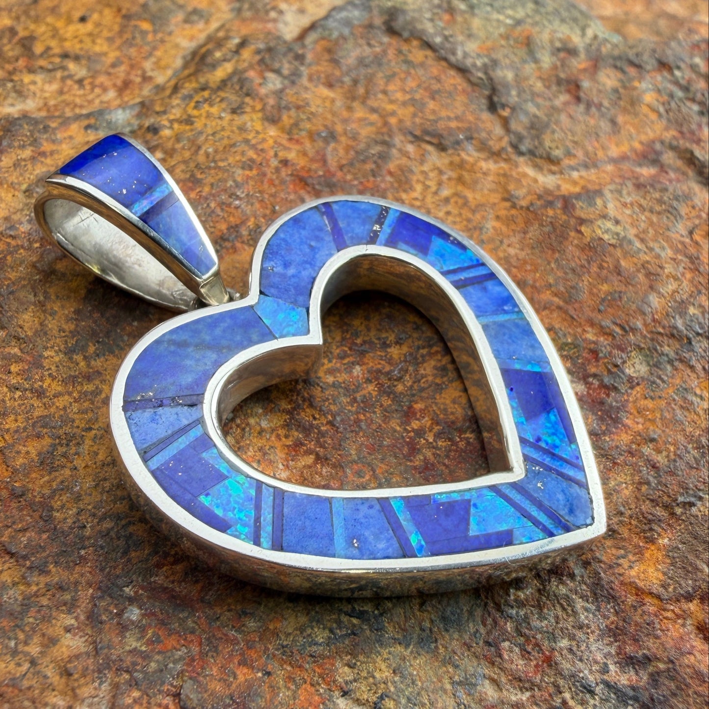 Heart-shaped pendant with blue mosaic design on a textured stone background