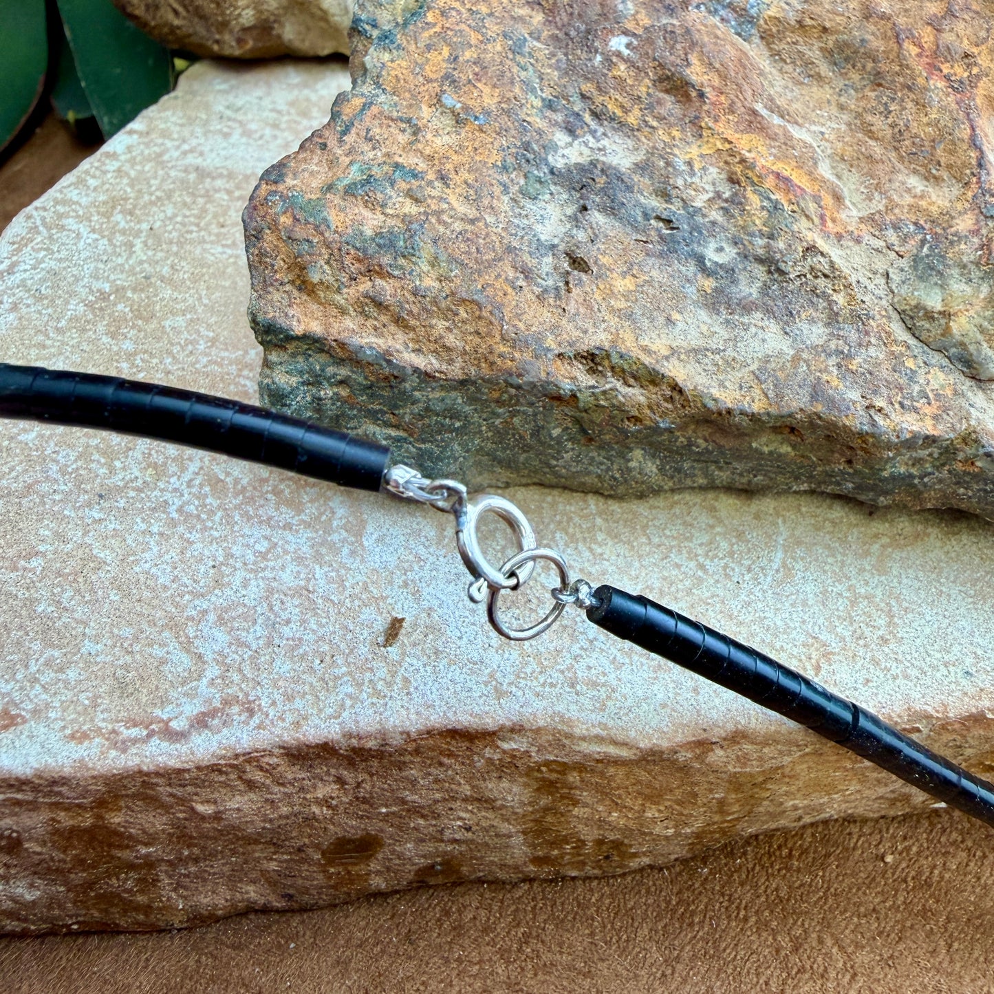 Black beaded end of a necklace with a silver clasp