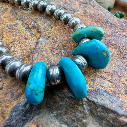 Necklace with turquoise and silver beads on a textured stone surface