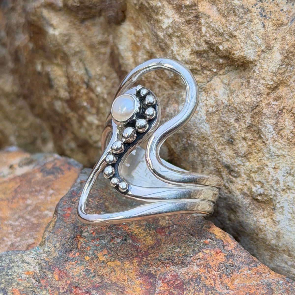Angled view of Ray Coriz sterling silver wave ring with freshwater pearl and open flowing bands
