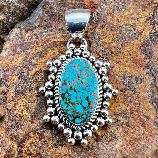 Turquoise pendant with silver beads on a stone background