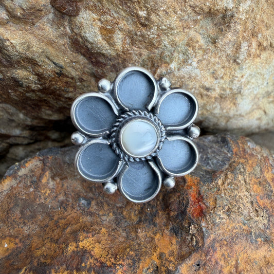 Silver flower-shaped ring on a textured stone surface