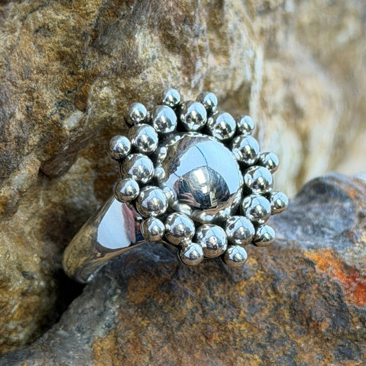 A polished sterling silver dome rises from the center, encircled by two concentric rings of hand-soldered silver shot beads that radiate outward in a sunburst pattern.
