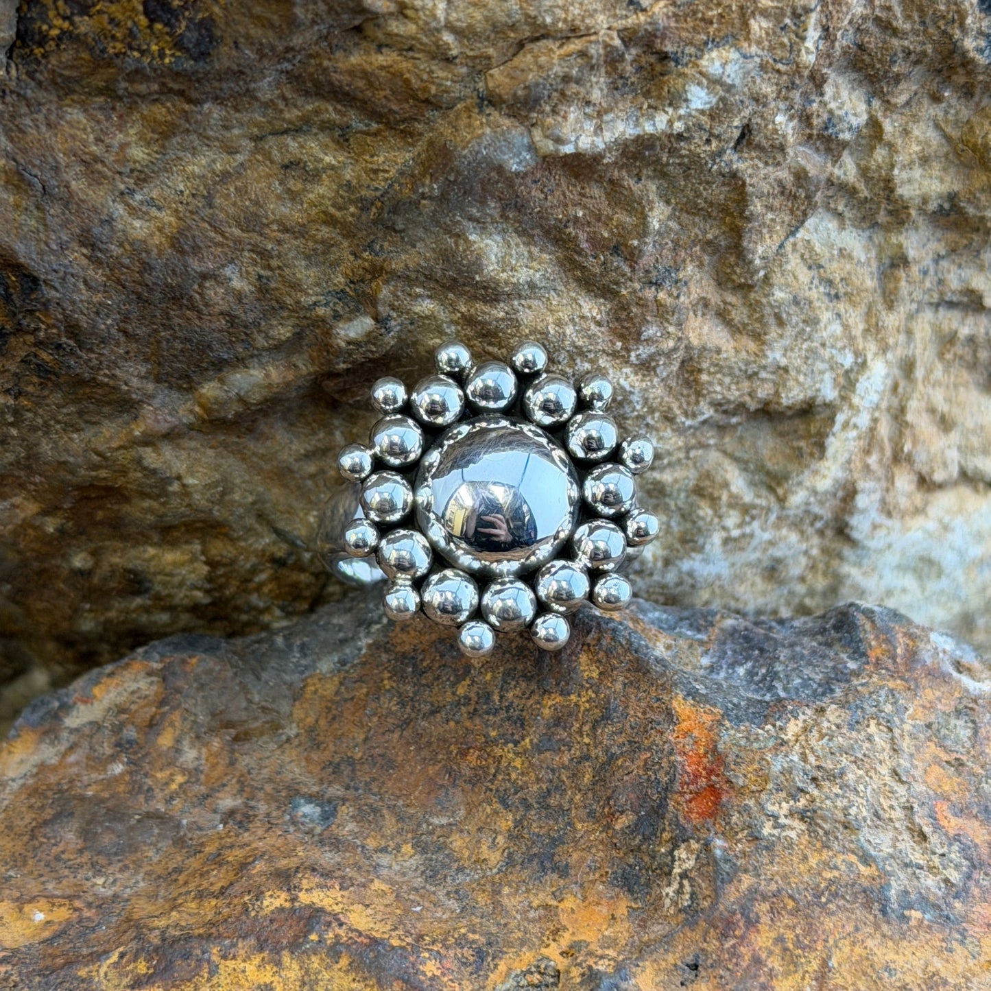 A polished sterling silver dome rises from the center, encircled by two concentric rings of hand-soldered silver shot beads radiating outward in a sunburst pattern.
