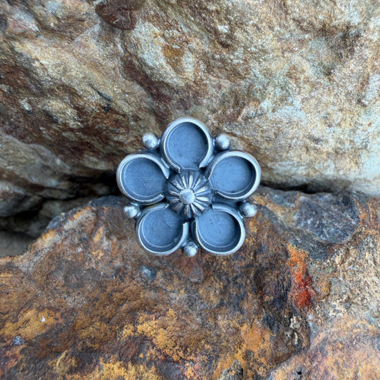 Silver flower-shaped object on a textured stone surface