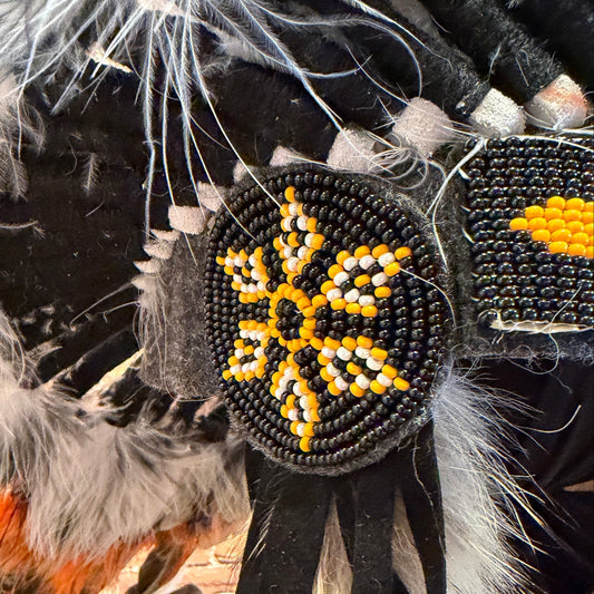 Decorative item with beads and feathers against a brick wall background