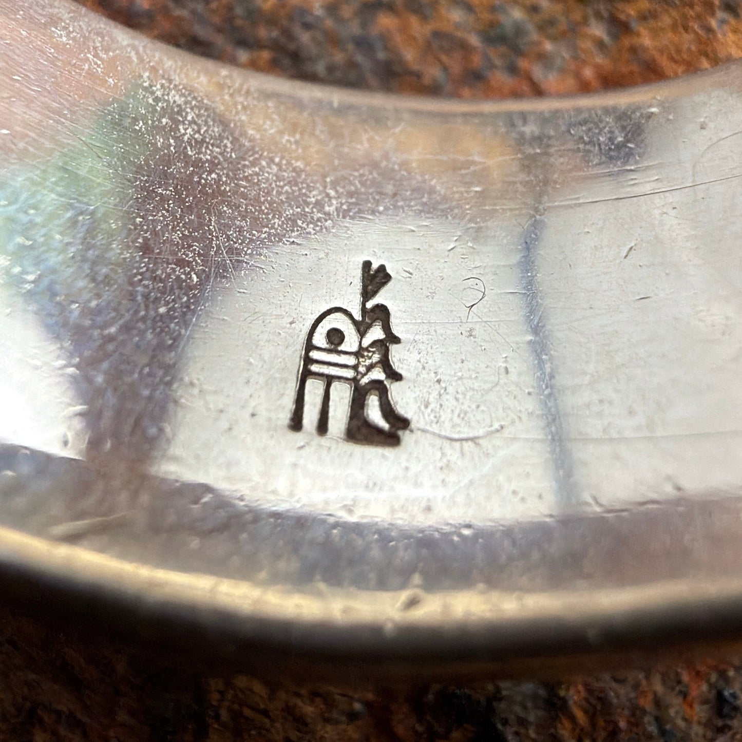 Close-up of a metal object with a logo on a rock background