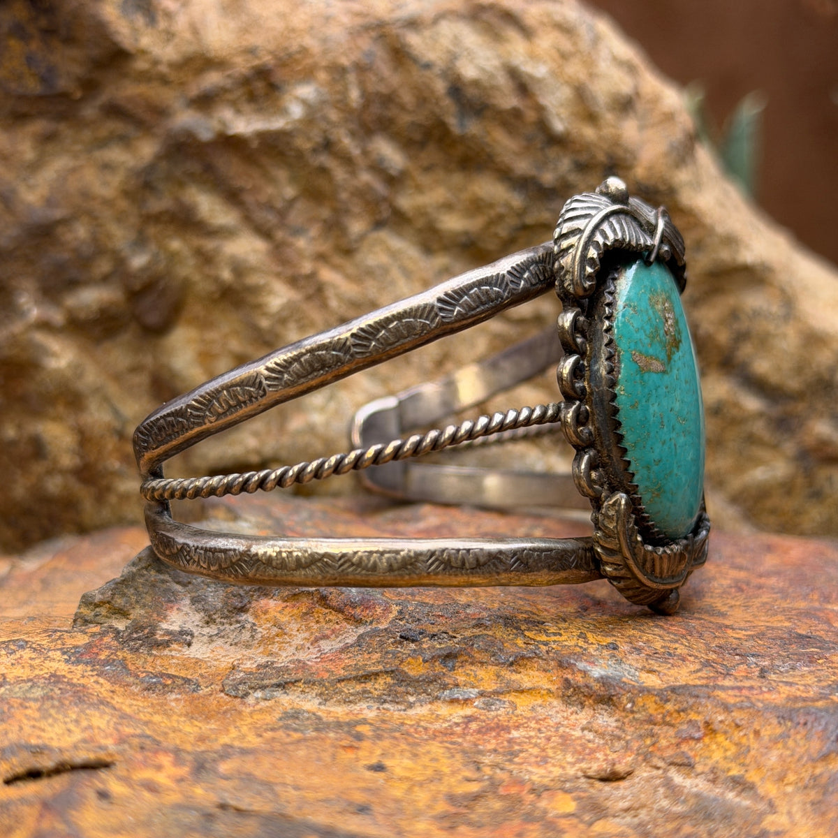 Angled view of vintage sterling silver turquoise leaf-detail cuff bracelet