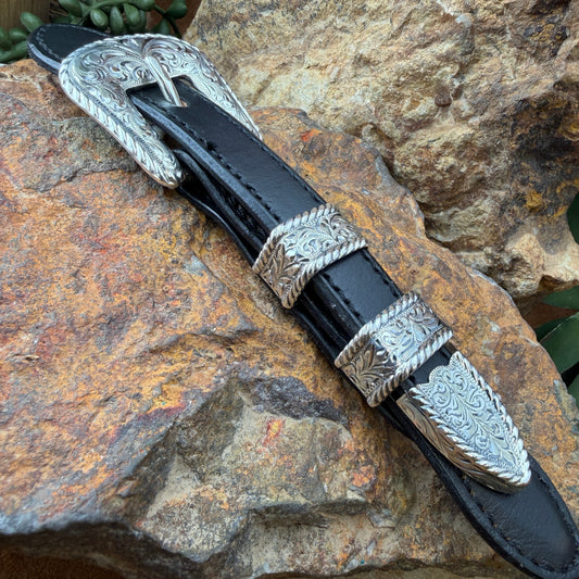 Black leather belt with silver buckle on a stone surface