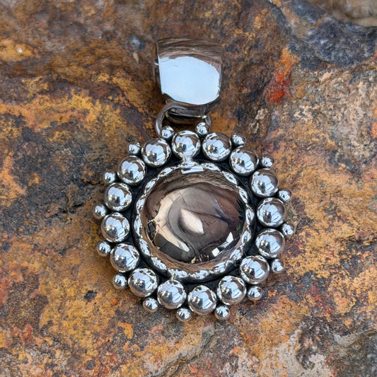 A central dome pendant surrounded by large silver balls accented by smaller one. This pendant is created by Artie Yellowhorse
