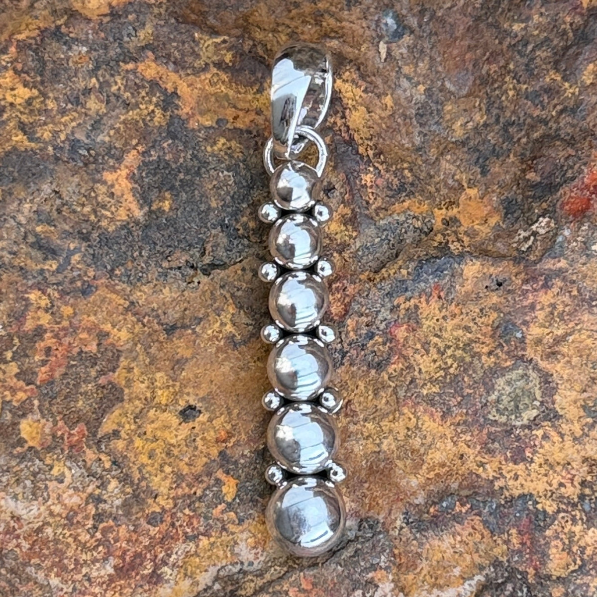 Angled view of Artie Yellowhorse six sphere sterling silver pendant