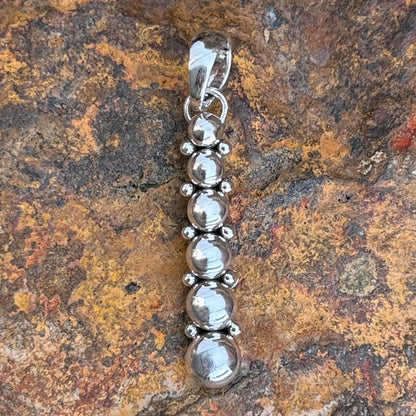 Angled view of Artie Yellowhorse six sphere sterling silver pendant