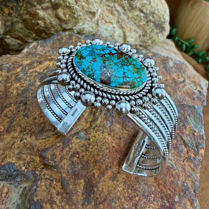 Kingman Turquoise Cuff Bracelet by Artie Yellowhorse - styled view showing full bracelet on rock with twisted rope band