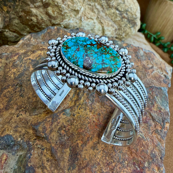 Kingman Turquoise Cuff Bracelet by Artie Yellowhorse - styled view showing full bracelet on rock with twisted rope band