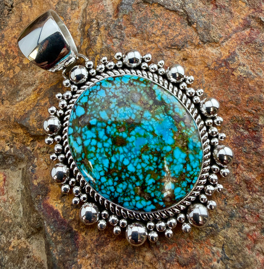 Kingman Turquoise Oval Pendant by Artie Yellowhorse - front view showing vivid spiderweb matrix and silver bead halo