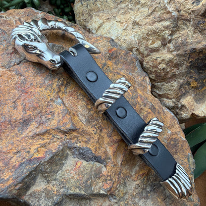 Black leather belt with silver metal buckle on a rocky surface