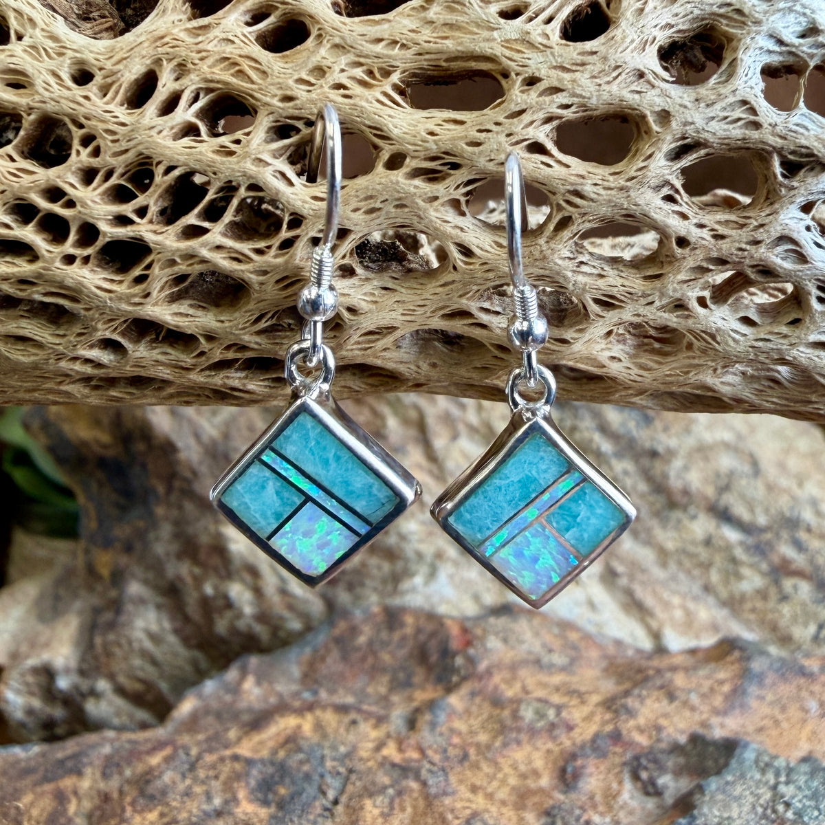 square earrings with opals and blue coloring hanging from cactus skeleton