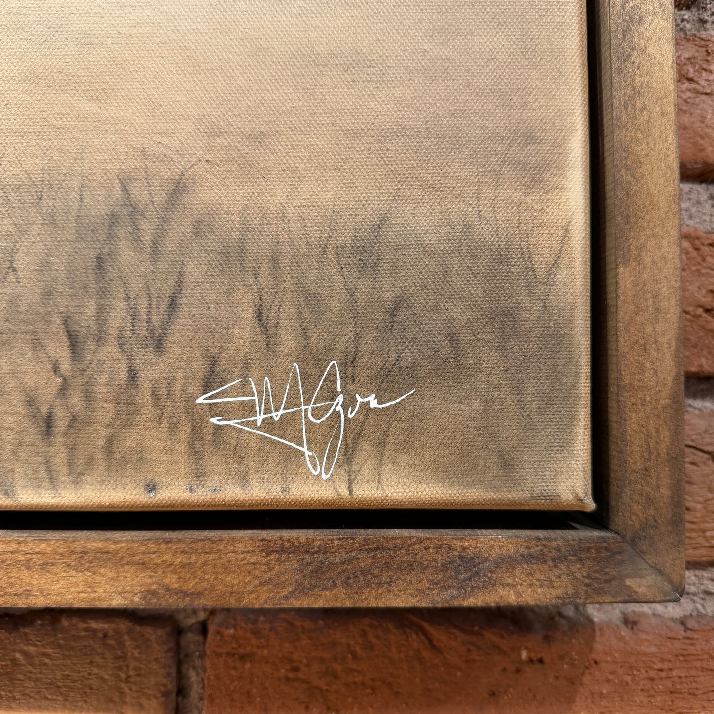 Signature on a textured surface with a wooden frame.