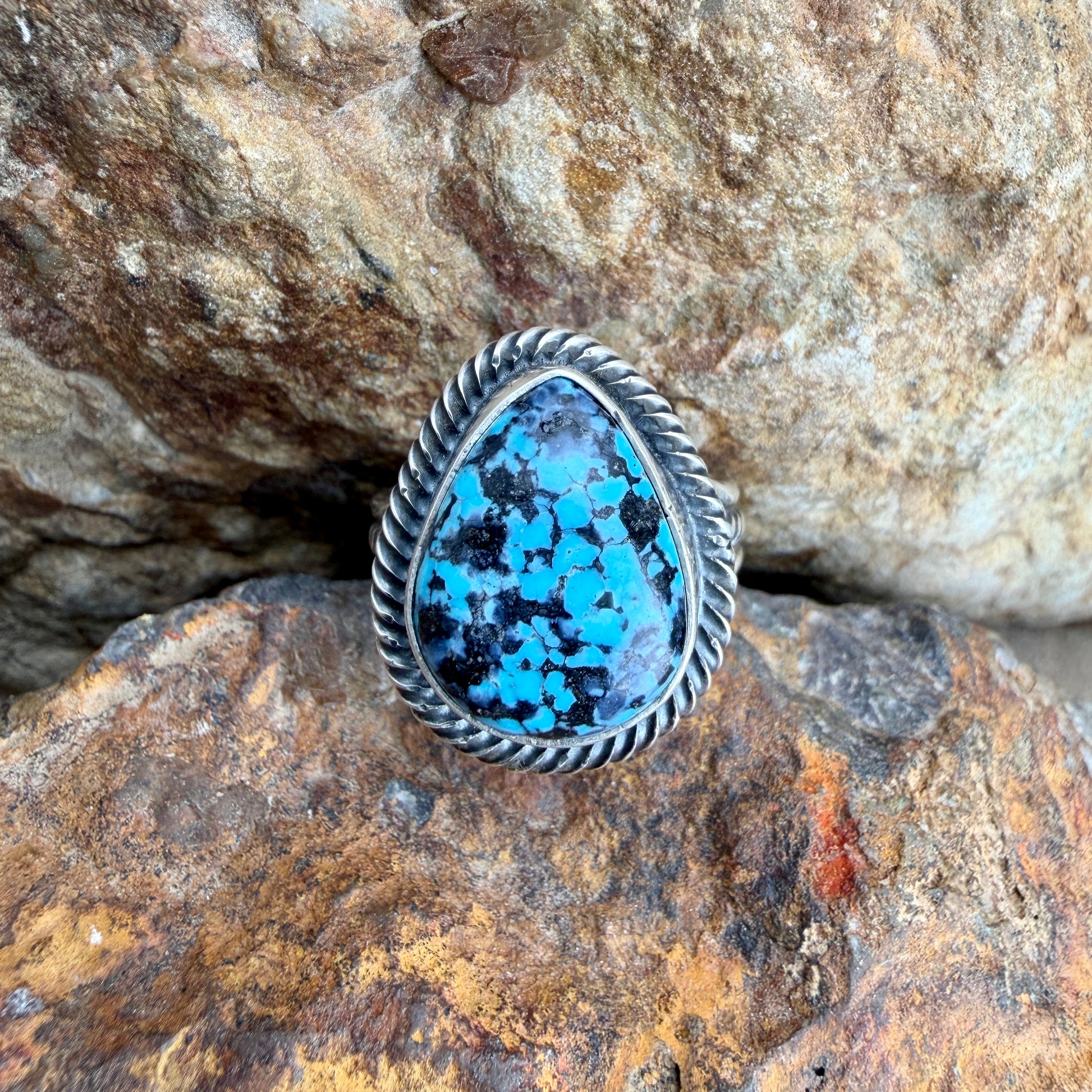 Silver ring with a blue stone on a rocky surface