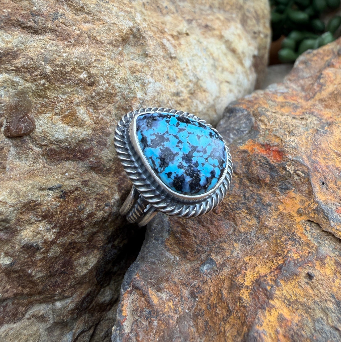 Silver ring with a blue stone on a rocky surface