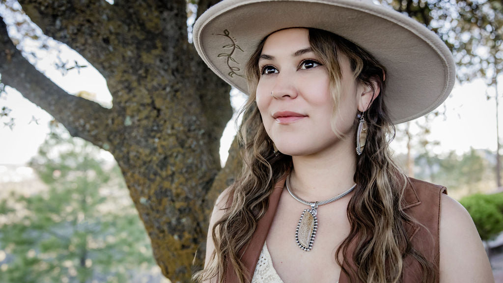 Woman wearing a wide-brimmed hat outdoors with trees in the background