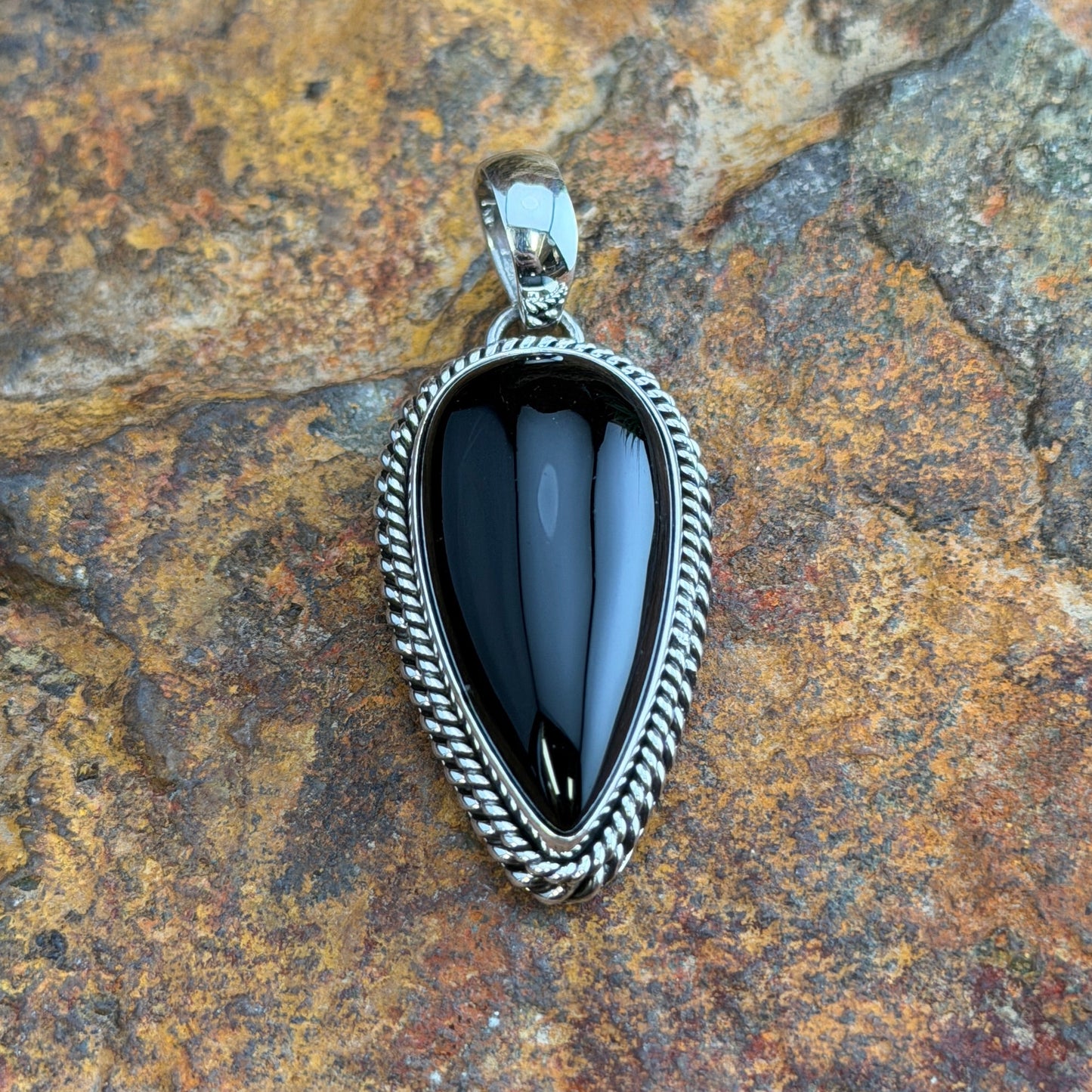 Black Onyx Pendant by Artie Yellowhorse - front view showing shield-shaped glossy black onyx in double twisted rope border