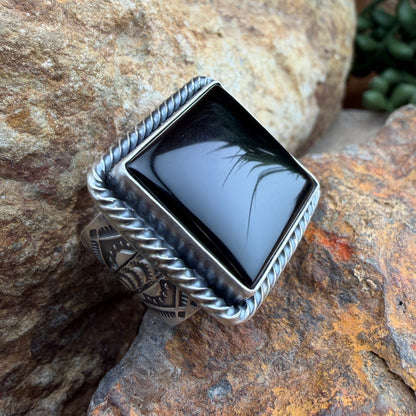 Silver ring with a black stone on a textured stone surface
