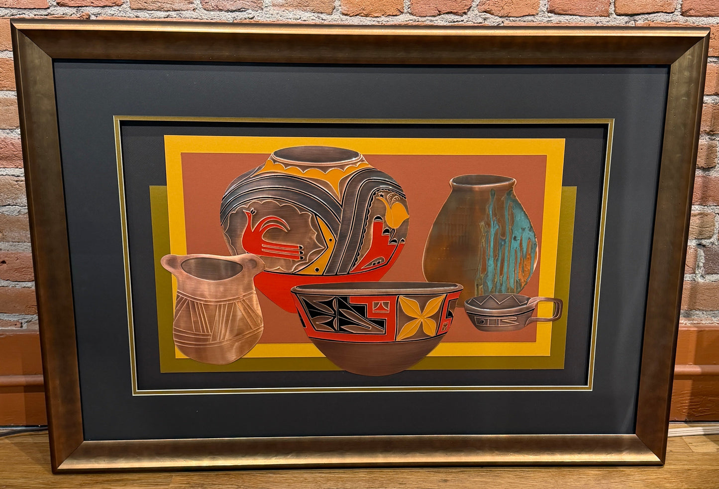 Framed artwork of ceramic pots against a brick wall.