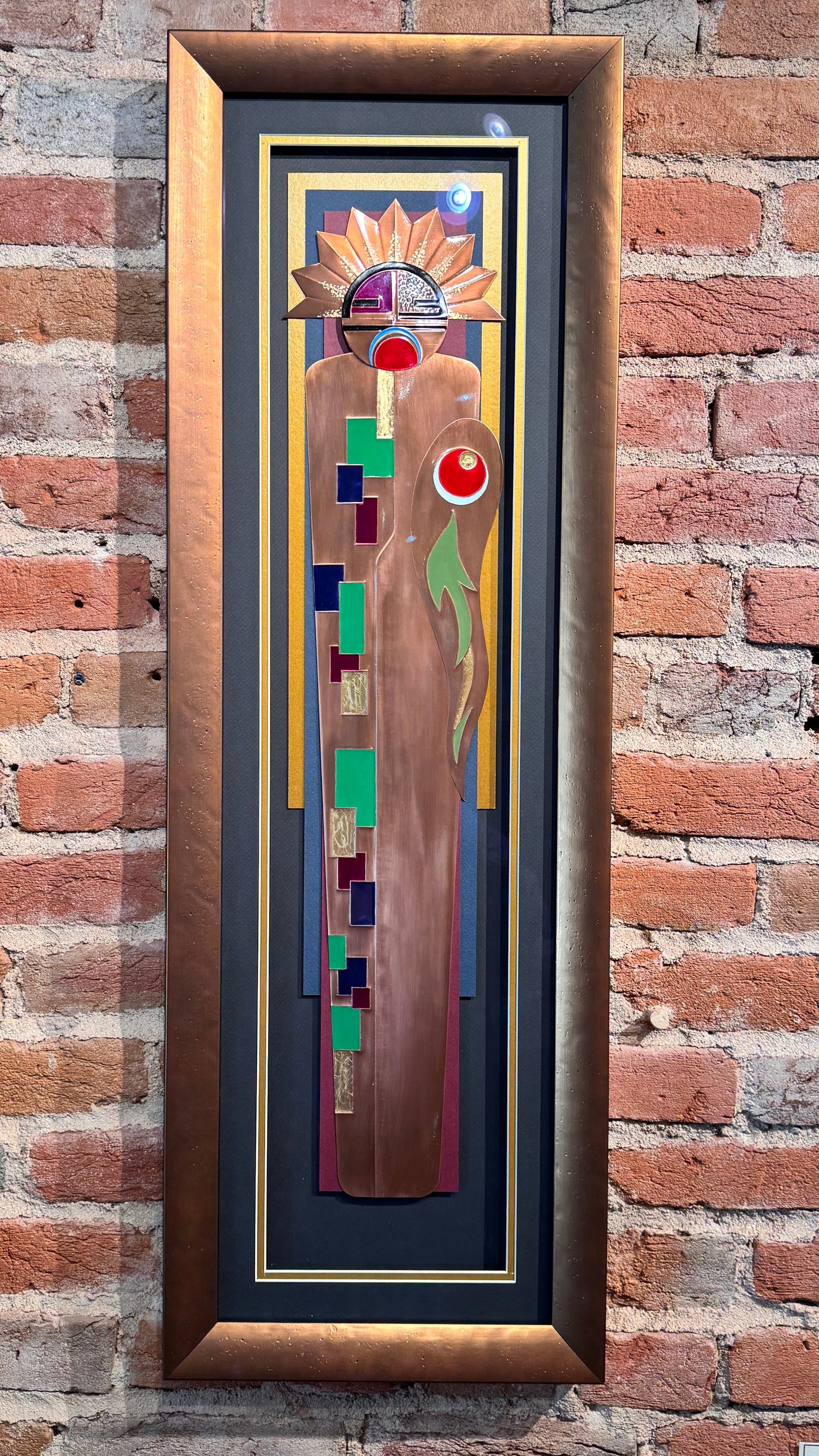 Framed abstract artwork on a brick wall