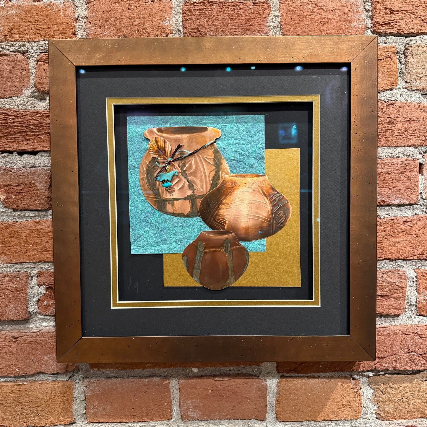 Framed artwork of three ceramic pots on a brick wall