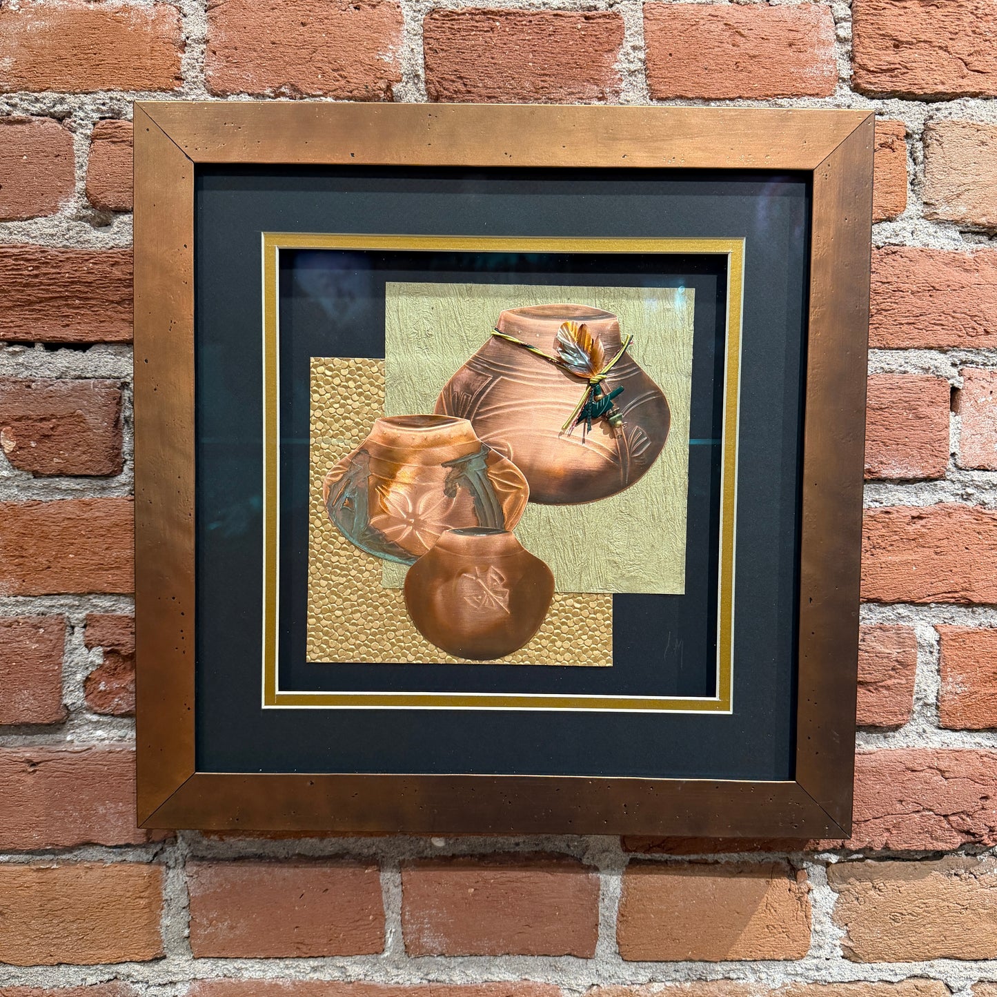 Framed artwork of ceramic pots on a brick wall