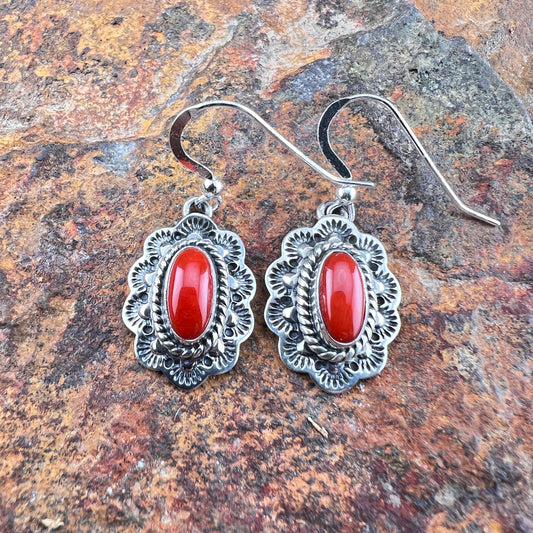 Silver earrings with red stones on a stone surface