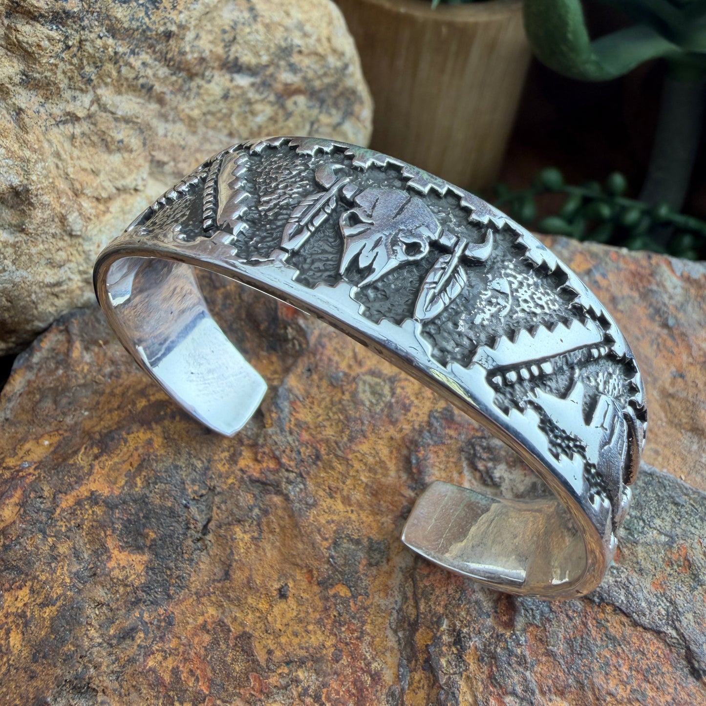 Silver bracelet with intricate designs  of a buffalo skull, landscape, and eagle