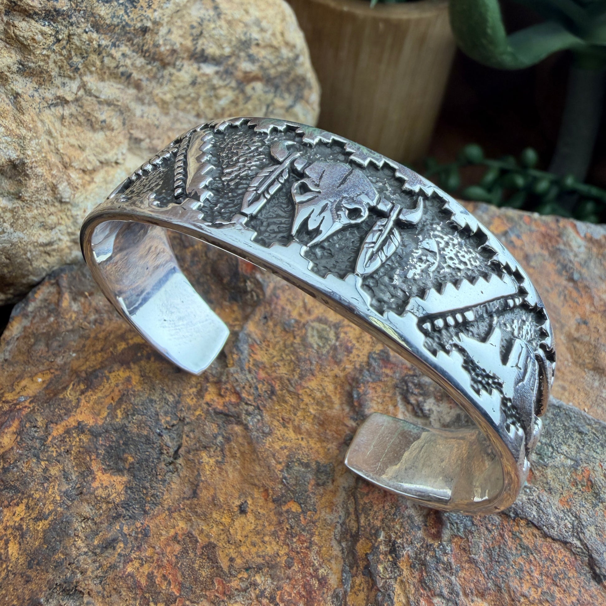 Silver bracelet with intricate designs  of a buffalo skull, landscape, and eagle