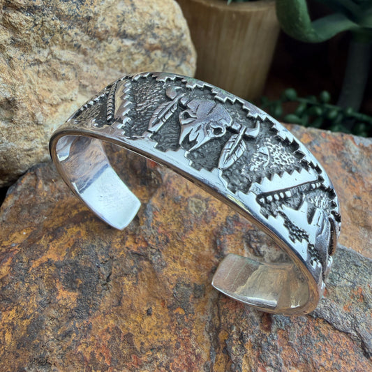 Silver bracelet with intricate designs  of a buffalo skull, landscape, and eagle