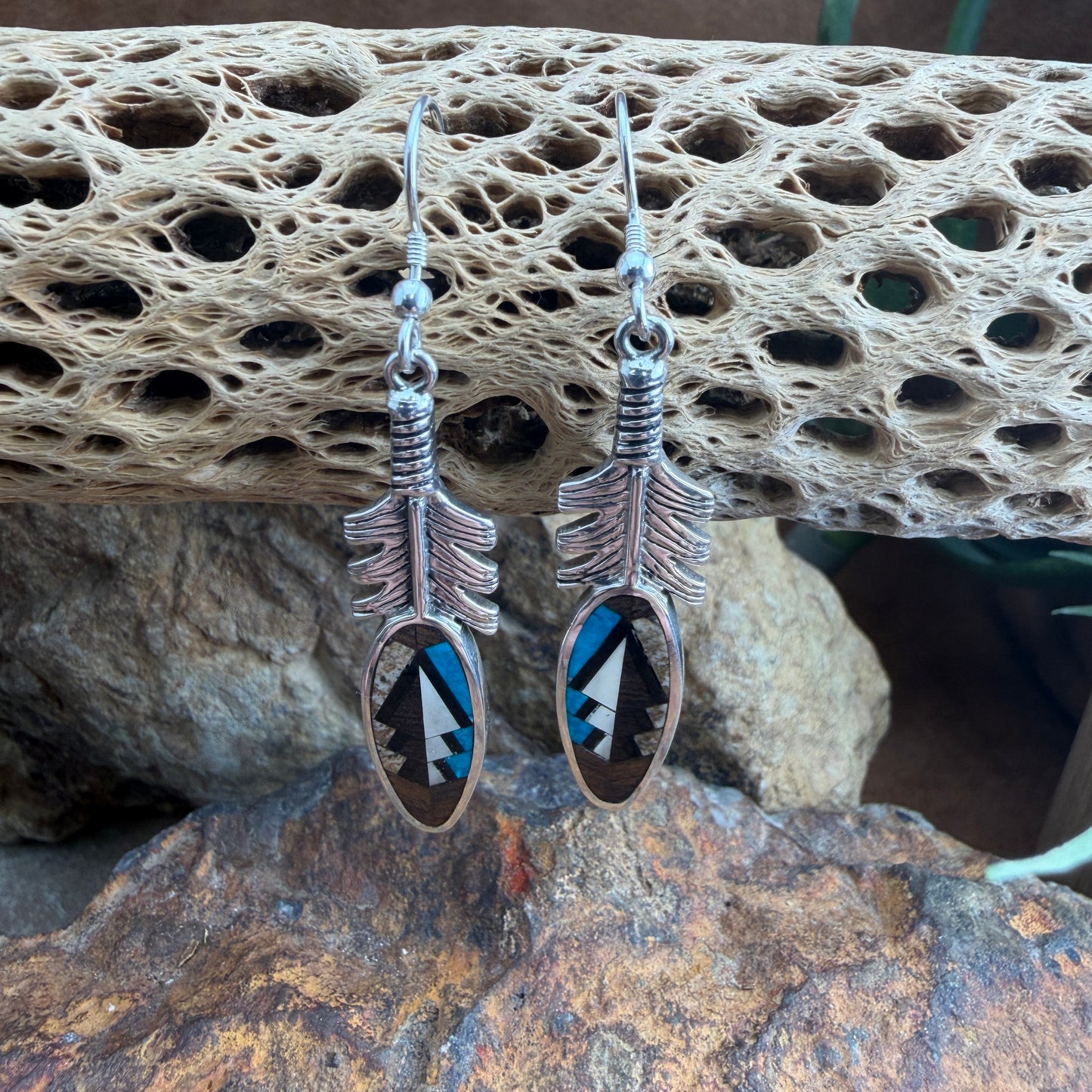 Silver feather-shaped earrings with blue, brown and black designs 