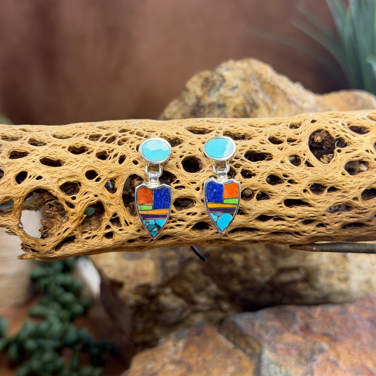 Pair of drop post earrings that are sterling Silver Earings with blue, orange, purple, green stones inlaid throughout