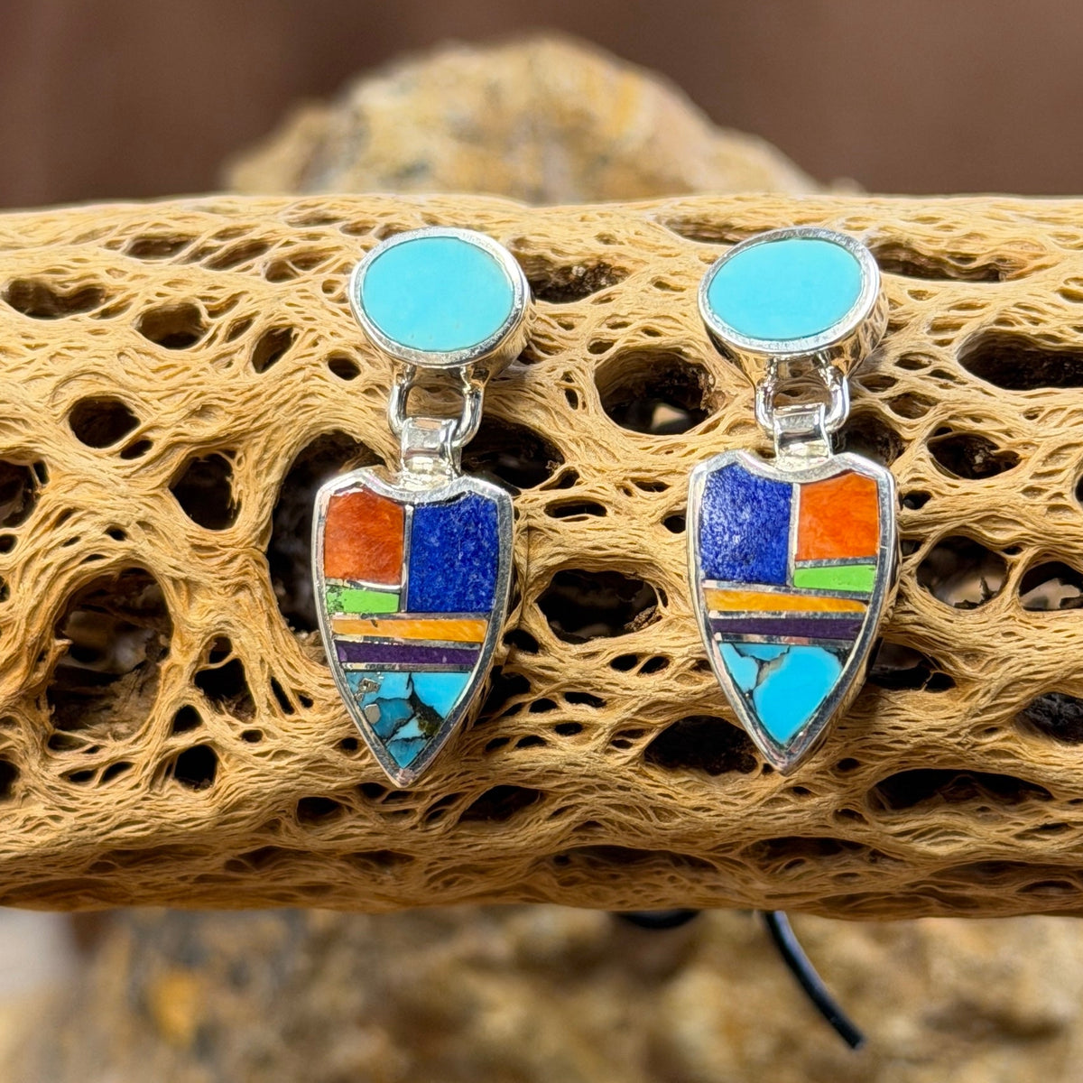 Pair of drop post earrings that are sterling Silver Earings with blue, orange, purple, green stones inlaid throughout