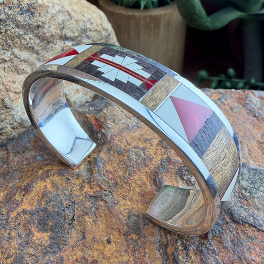 Multicolored red, brown and white inlay cuff bracelet on a stone surface