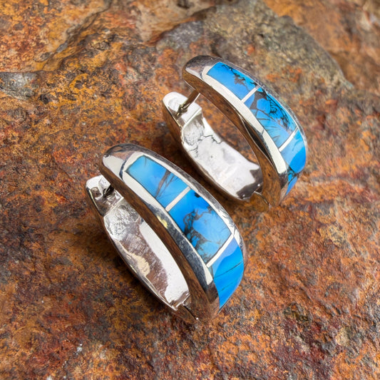 Pair of silver earrings with dolomite inlay on a textured rock surface