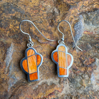 Pair of  cactus earrings with orange and silver design on a stone background