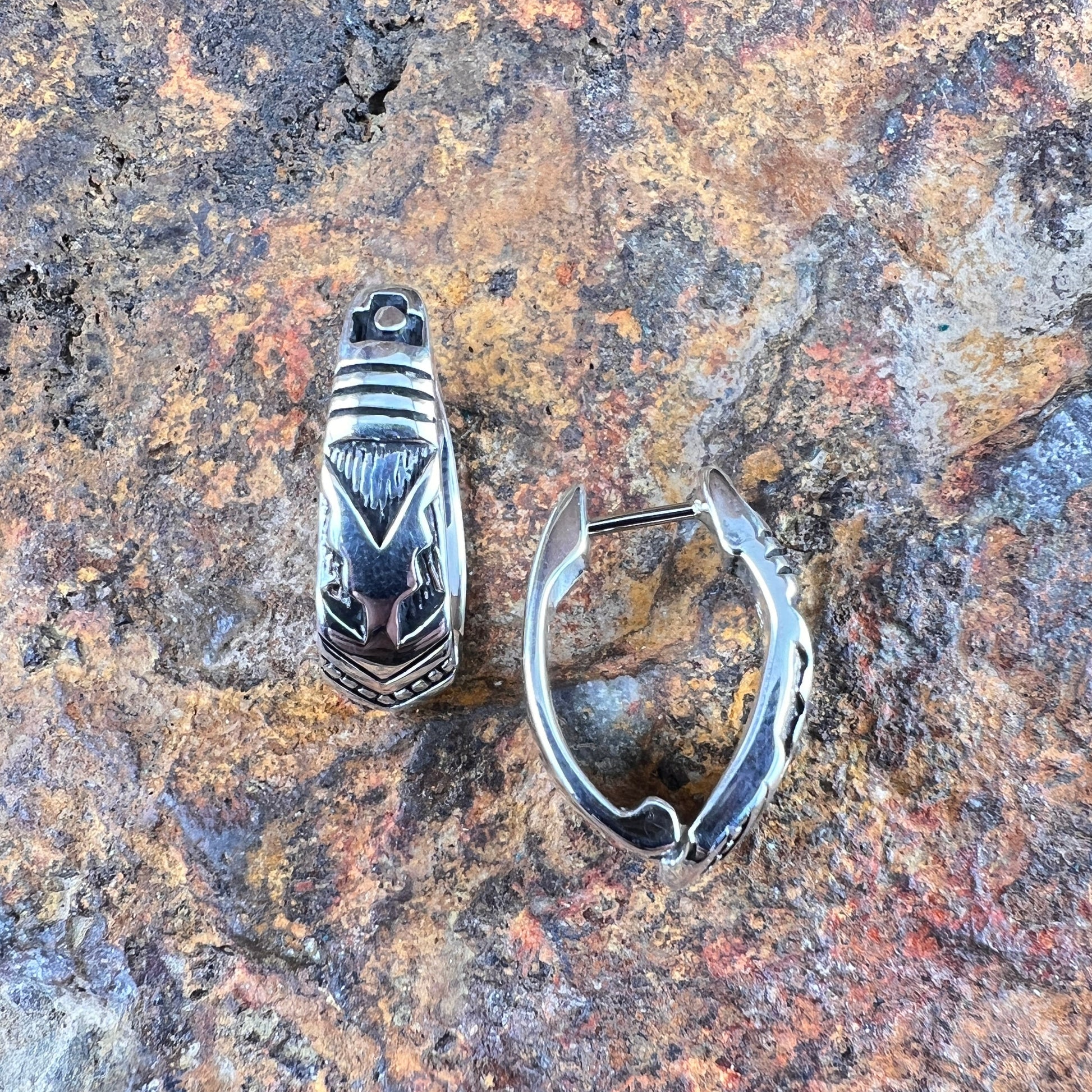 Silver ring and silver hoop earring on a textured stone surface